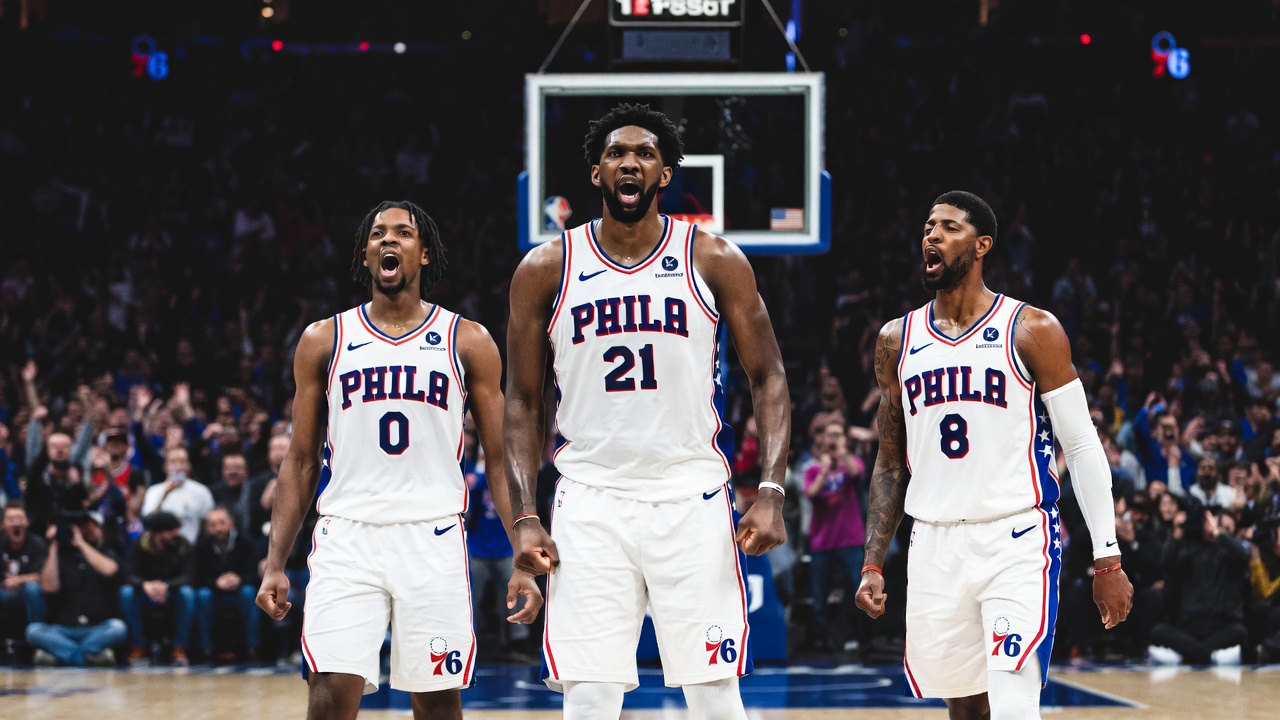Joel Embiid, Tyrese Maxey, and Paul George celebrating on the court after a big play, dynamic lighting, Philadelphia 76ers uniforms, crowd cheering in background, cinematic sports photography style